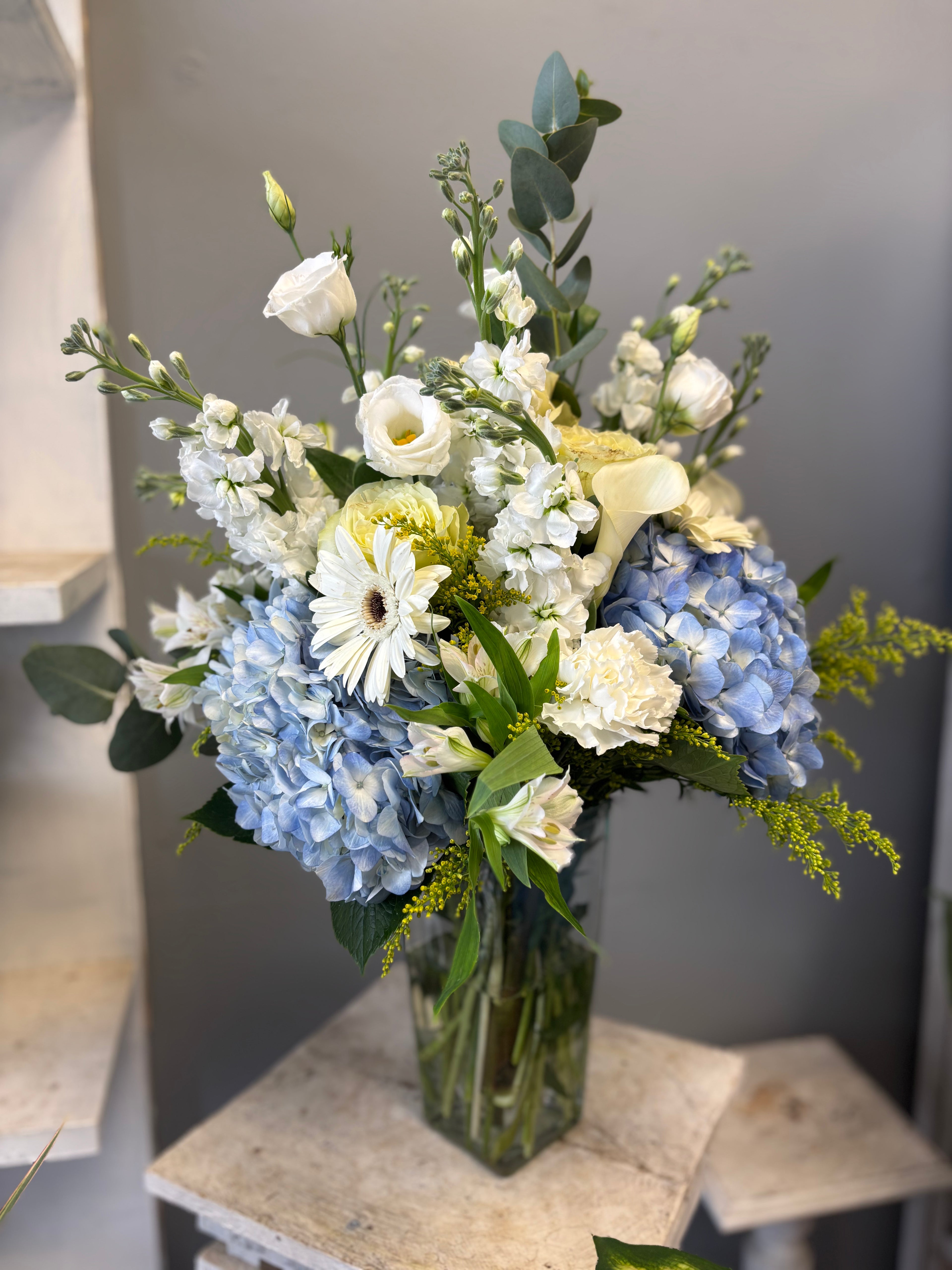 Tall, artistic, and full of movement, Something Blue is a dramatic arrangement designed in cool blues, whites, and flowing greenery. This piece reaches upward with elegance and intention, making it a true statement design.
Perfect for milestones, celebrations, and moments that call for something unforgettable.