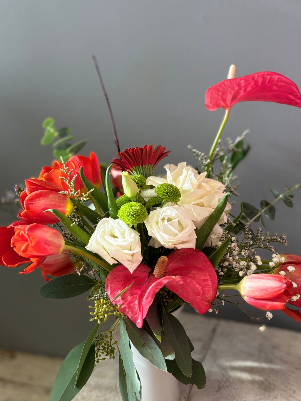 Sunward is a striking arrangement designed to reach upward and tell a story of warmth, resilience, and choosing hope.

Sculptural anthurium and vivid red tulips reach toward the light alongside a white rose, soft white lisianthus, deep red gerbera, and grounded with seasonal greens. Simultaneously bold and tender, it’s a reminder not to let the fire burn out, even in seasons of change.

Perfect for moments of encouragement.